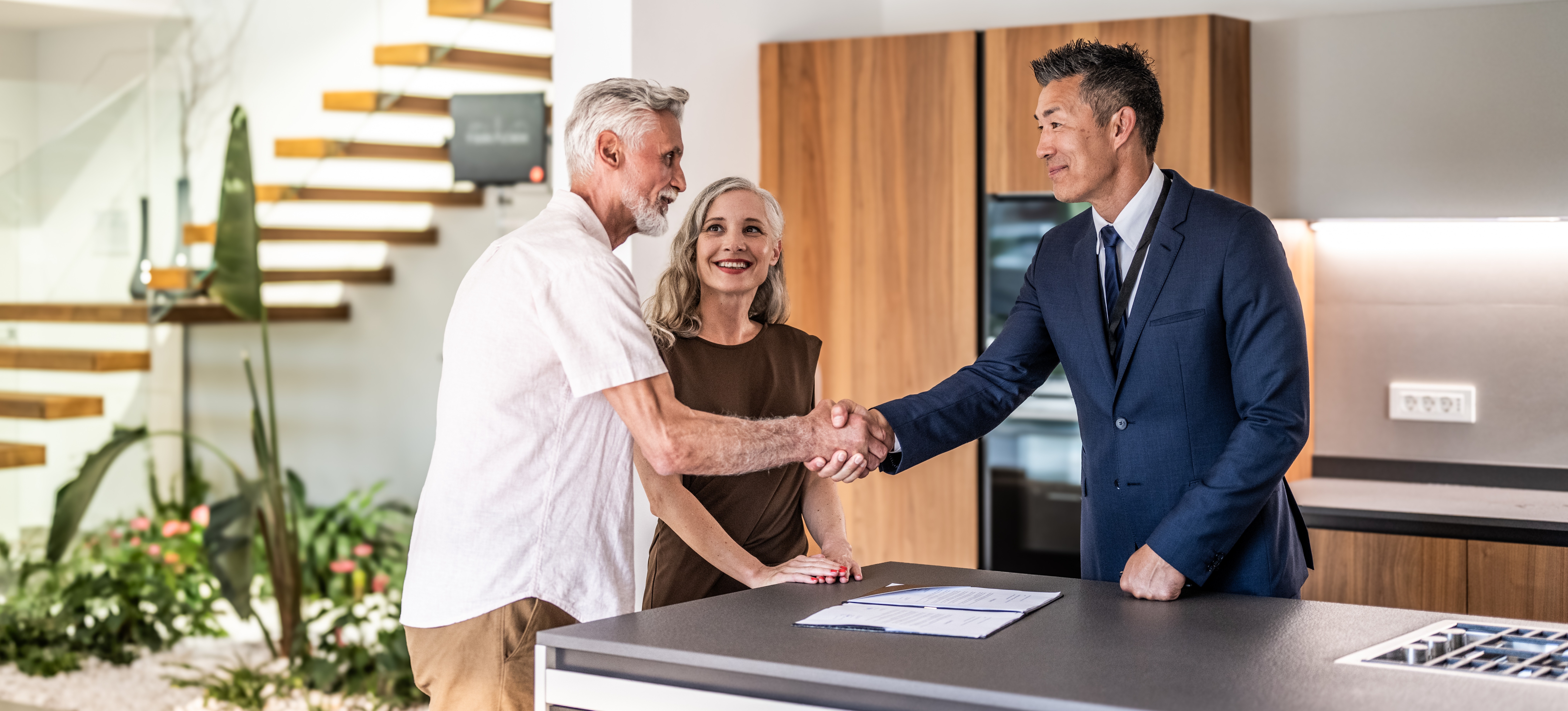 [Featured Image] A real estate agent shakes hands with a seller after closing a deal, demonstrating how they get paid.
