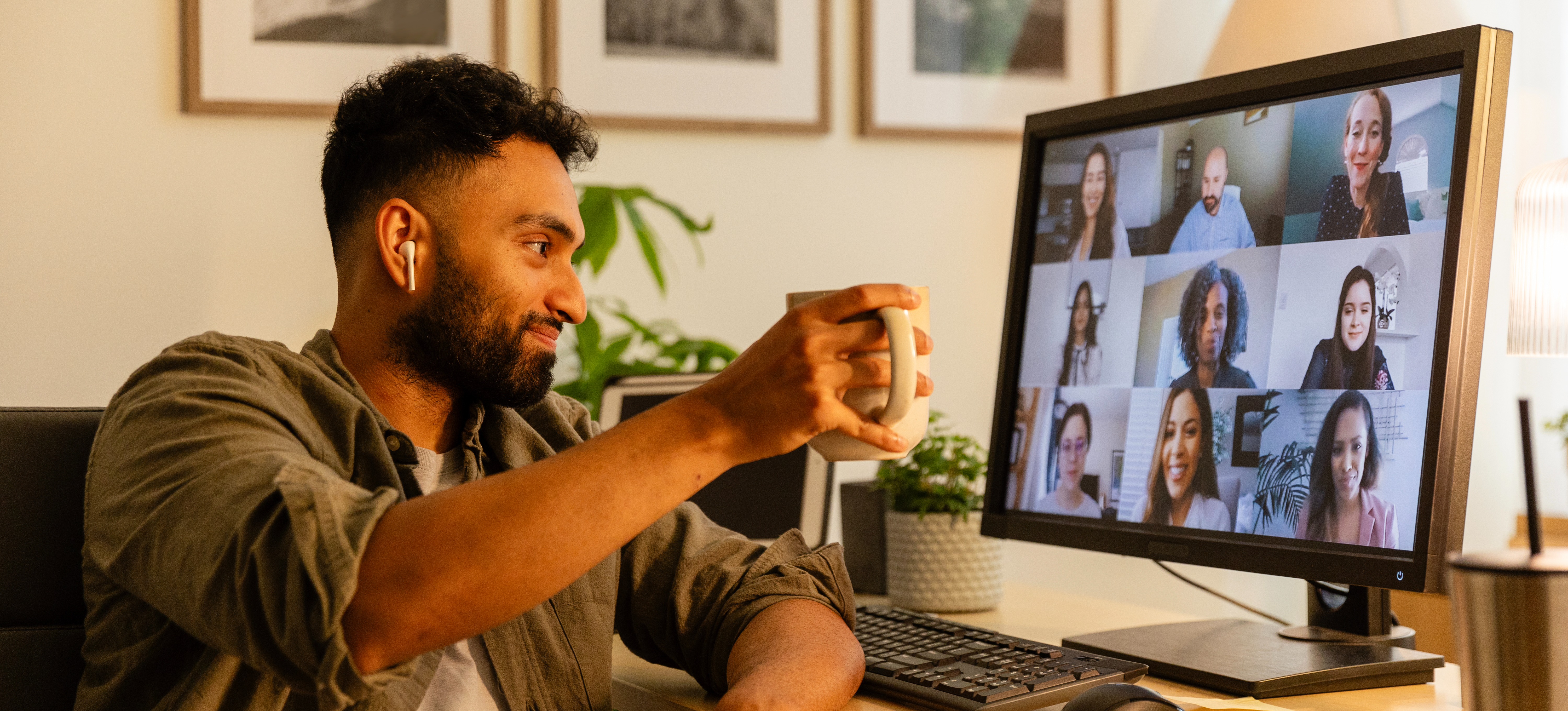 [Featured Image] A business owner sits at a computer in a virtual meeting with a coffee cup and discusses how Web3 technology may impact their company. 