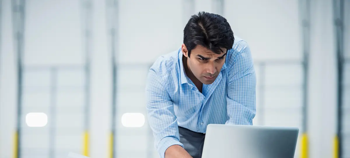 [Featured Image] An engineer in business attire stands in their well-lit office, looking at their computer as they pursue MATLAB certification.

