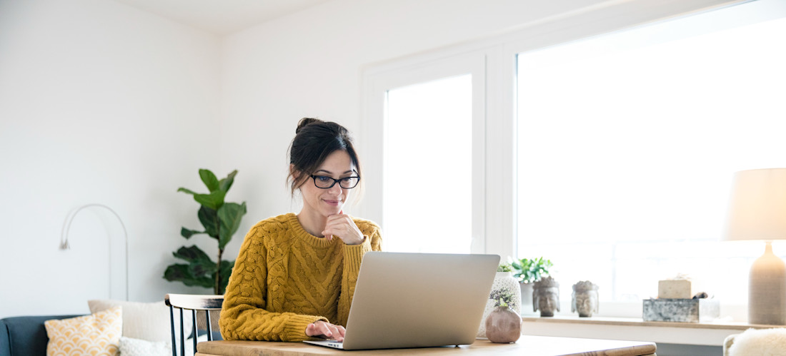 [Featured image] A woman is at home using her laptop to search for entry-level marketing jobs.
