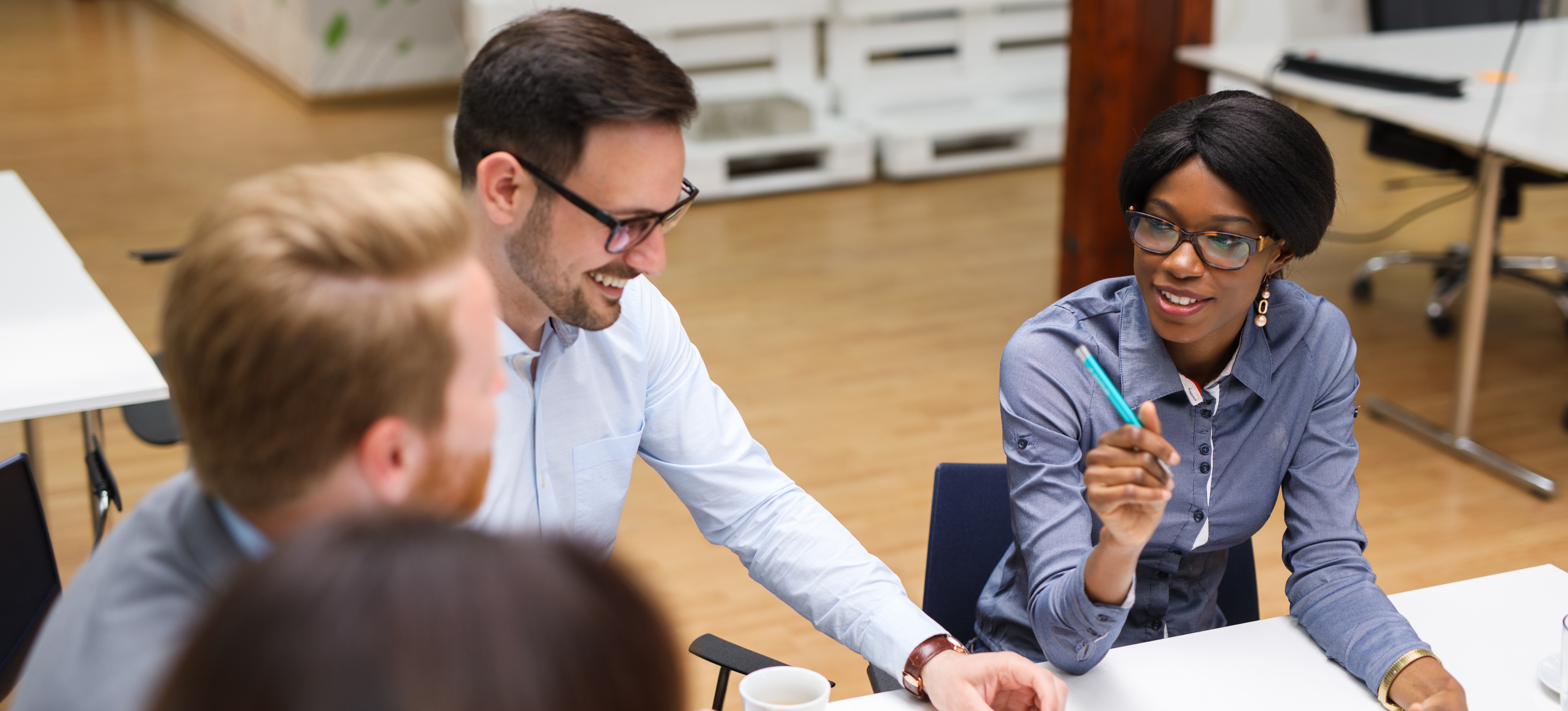 [Featured Image] Four colleagues sit in a meeting discussing printed and digital charts made with the help of their Tableau certification.
