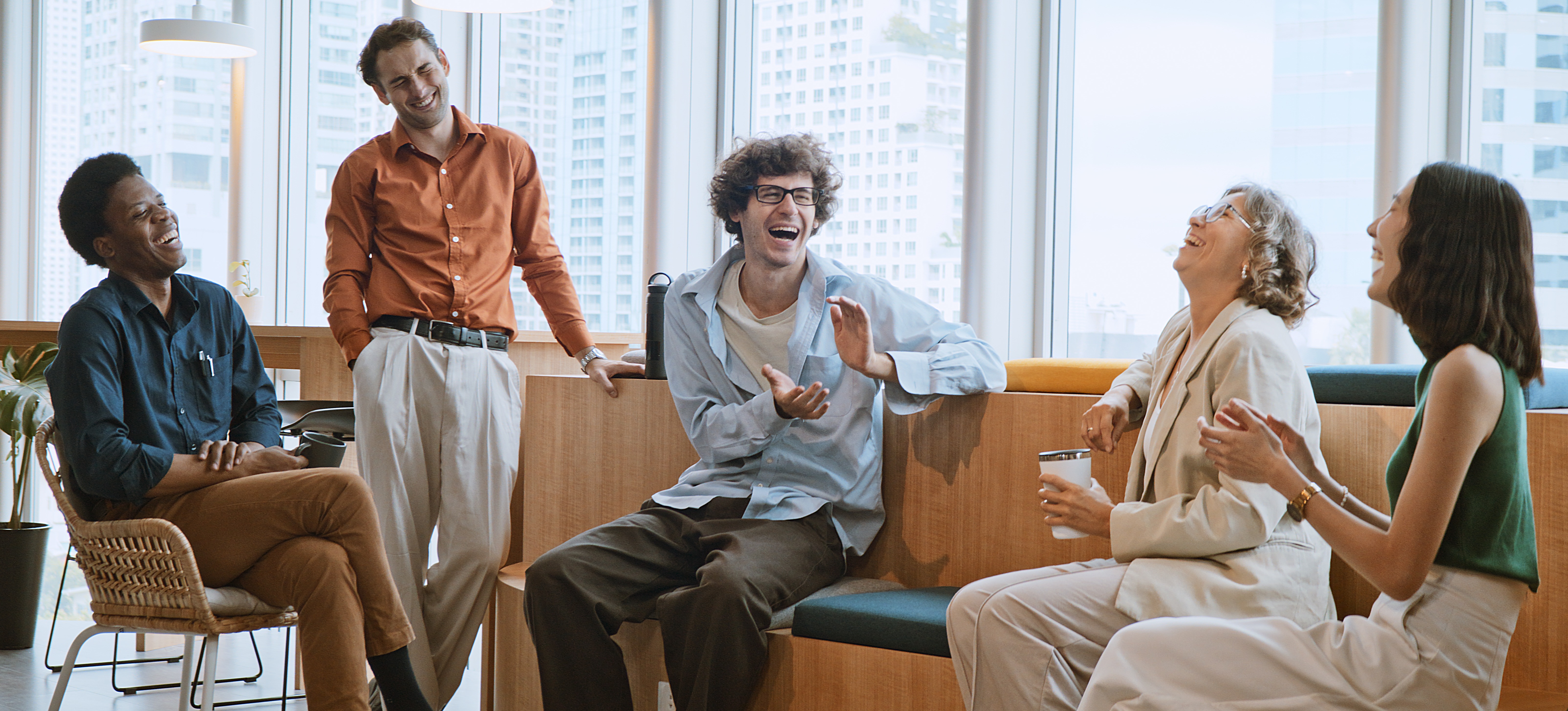 [Image en vedette] Un groupe de collègues rieurs sont assis dans un bureau et travaillent sur les compétences de renforcement d'équipe dans le cadre du développement des employés.