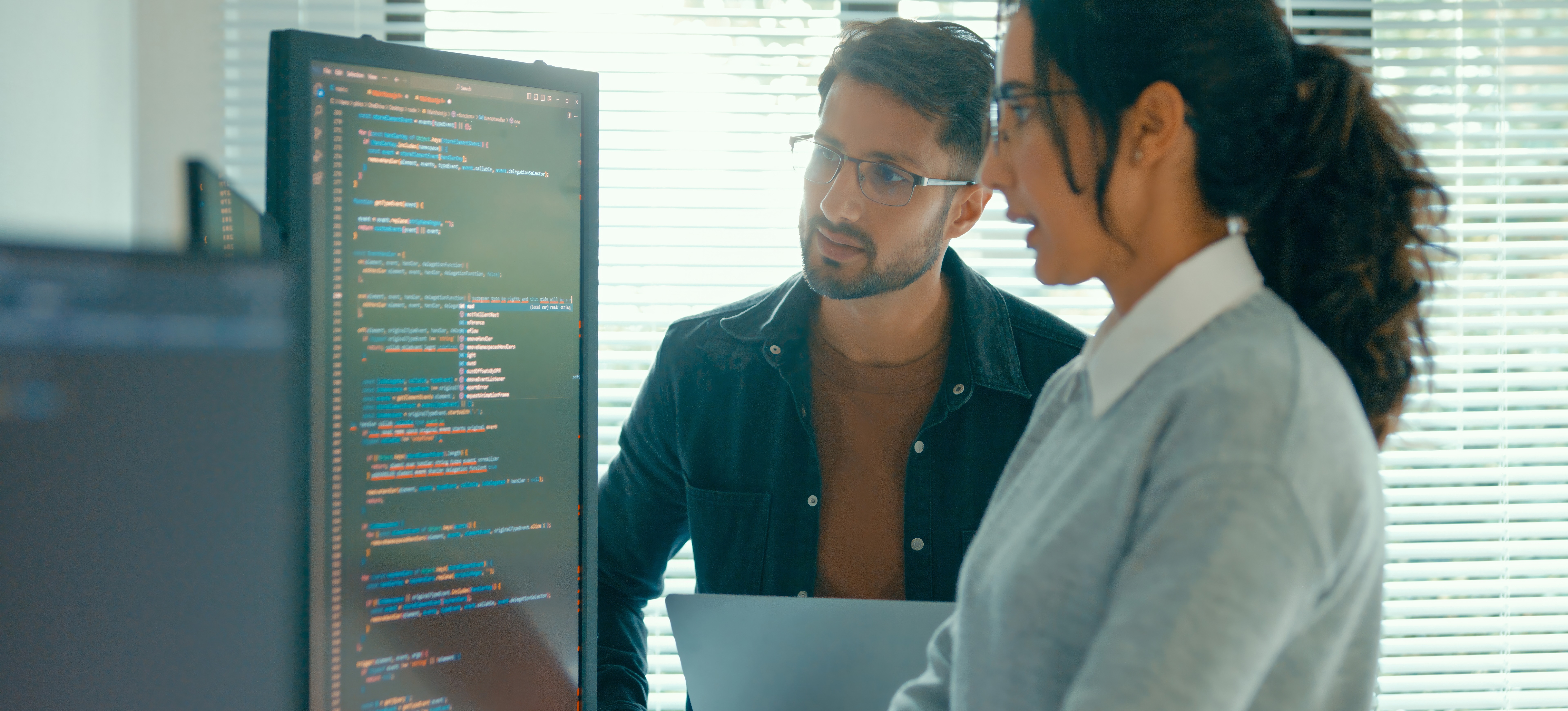 [Featured Image] Two data scientists look at a computer screen as they discuss data integrity.