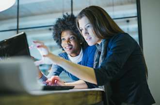 [Featured Image] A pair of UX designers looks at a computer while working on their design sprint.