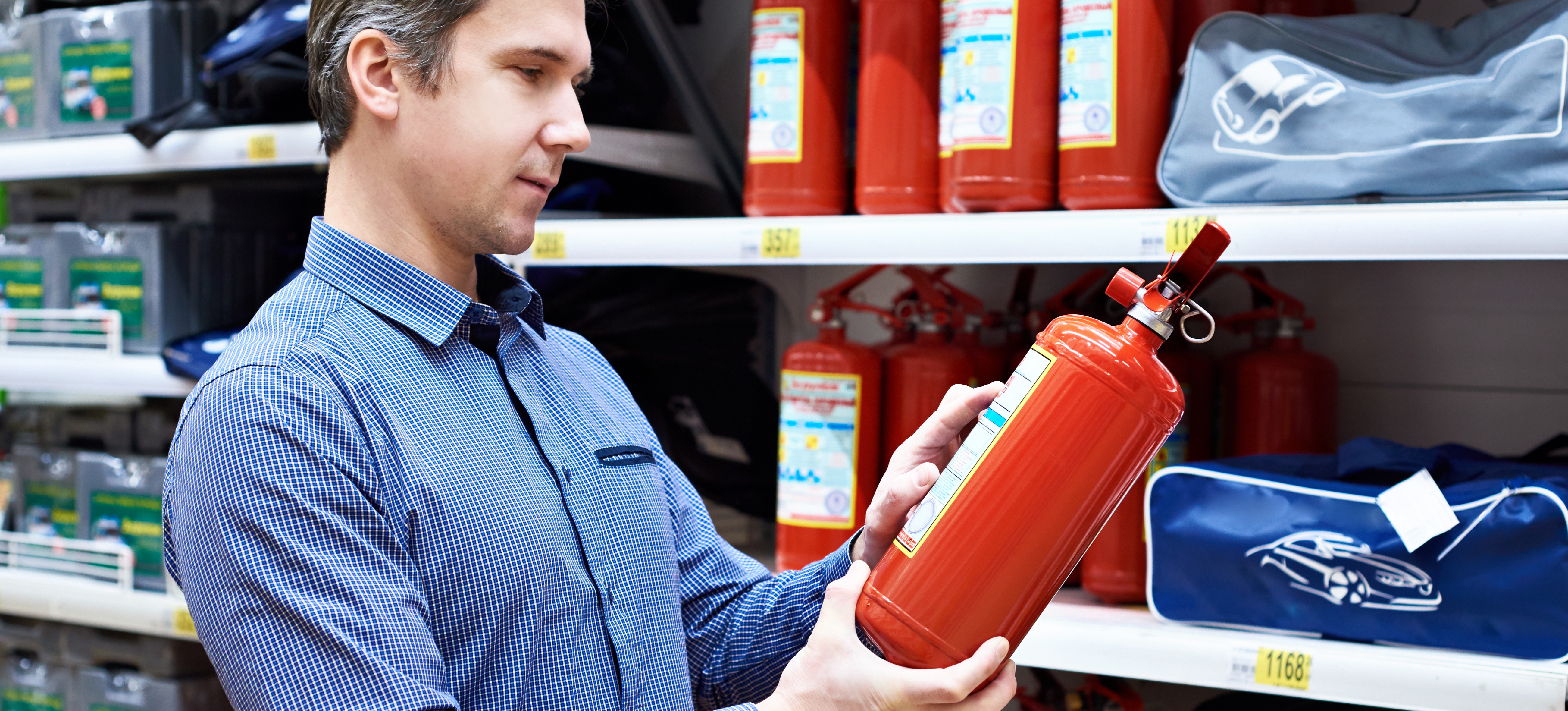 [Featured Image] A person is reading the label of a fire extinguisher, which is considered an unsought product. 
