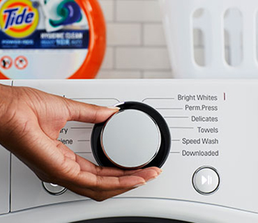 A person selecting the wash cycle on a washing machine