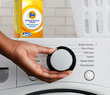 A person selecting the wash cycle on a washing machine