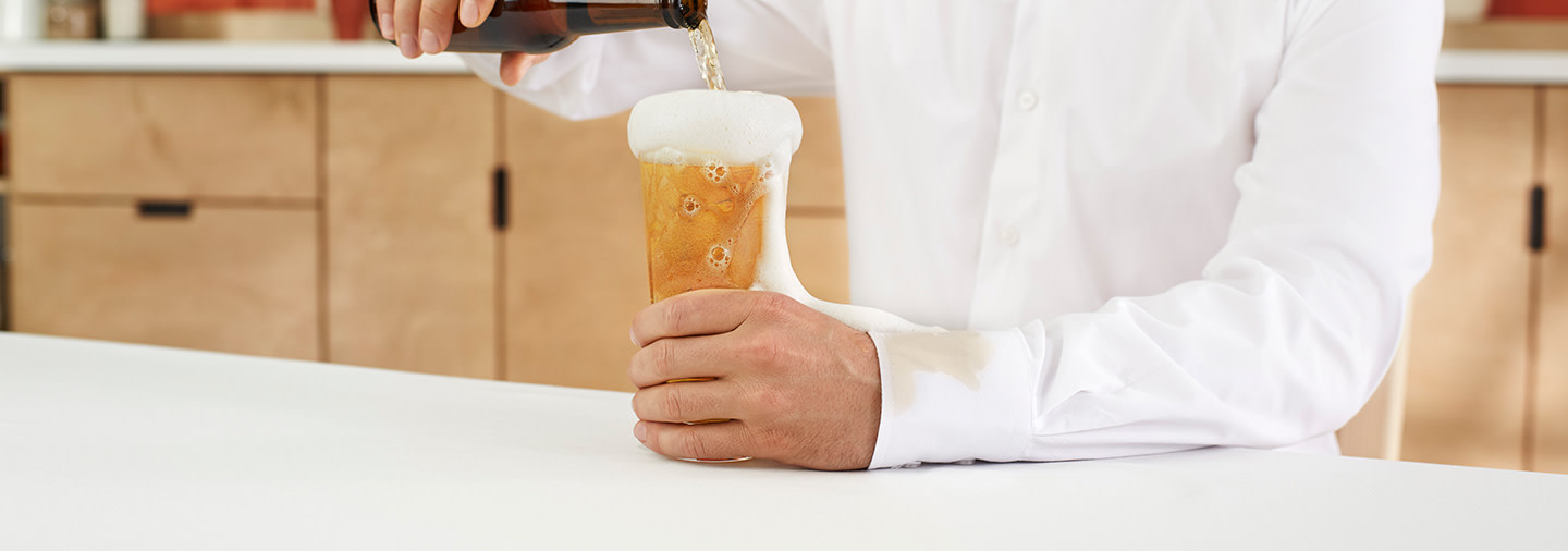 A person in a white shirt pouring beer into a glass