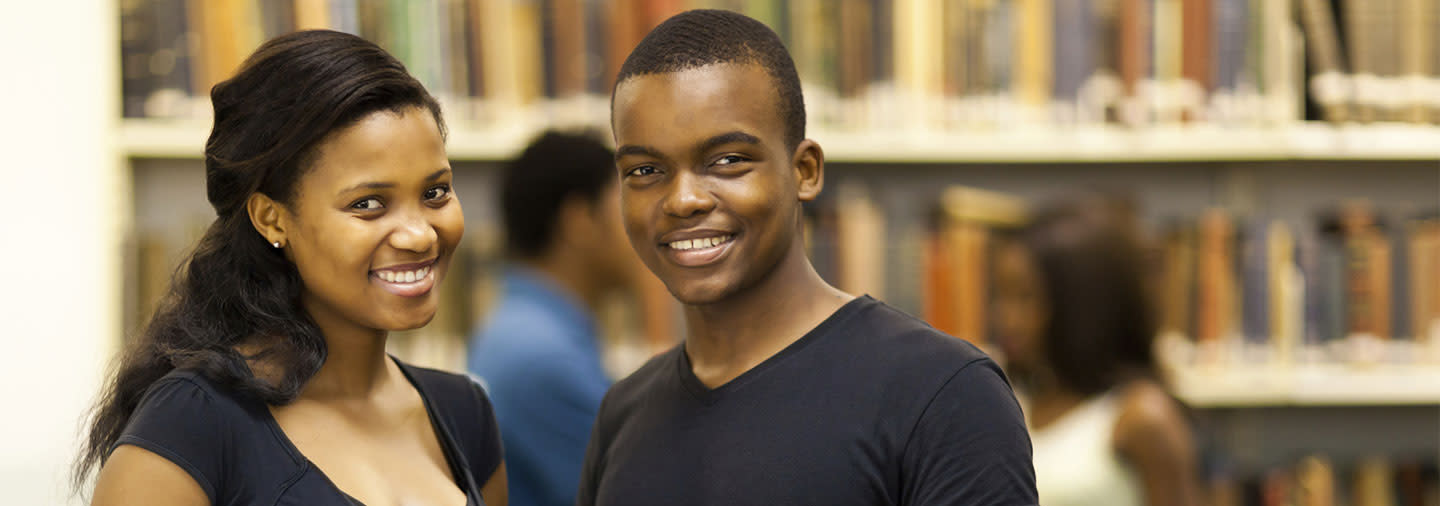 Two college students smiling in a library