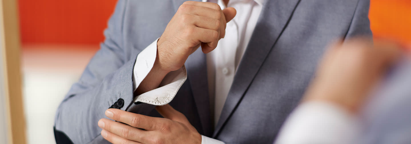 A man in grey suit adjusting his cuff-links