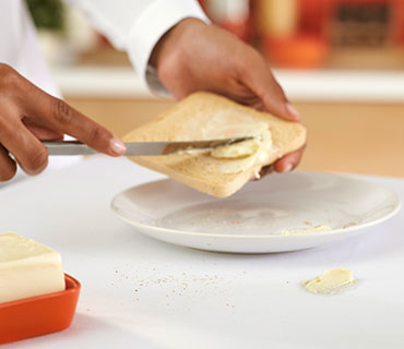 A person spreading butter on a slice of toast