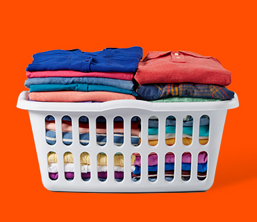 A laundry basket full of neatly folded, coloured gaments