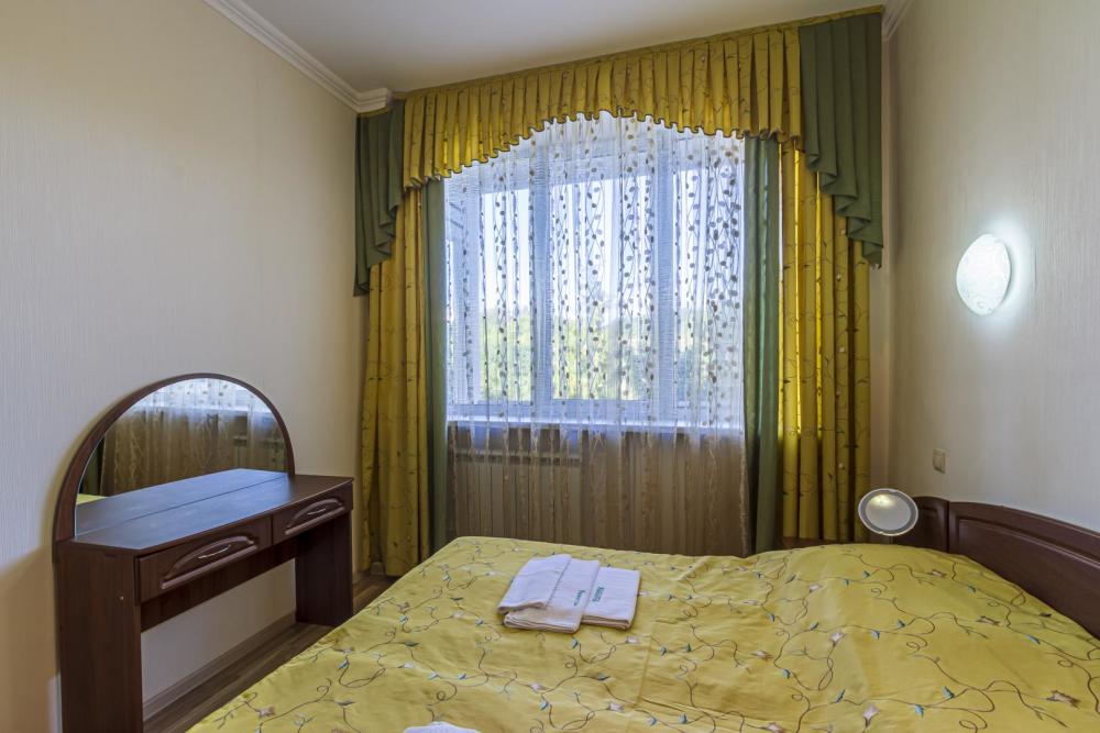 номер Люкс в санатории Узбекистан - двуспальная  кровать и тумбочка