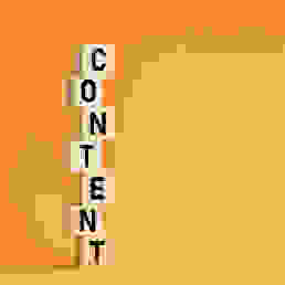 Blocks with letters on them stacked on top of each other to spell the word content. Bright orange background