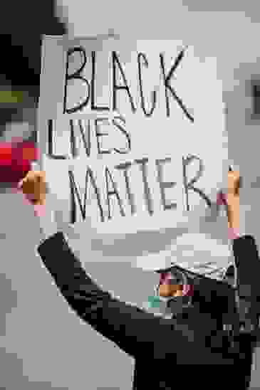 Masked person holding up a Black Lives Matter sign.