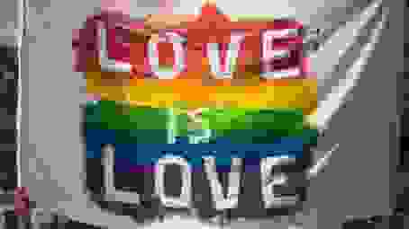 white flag with pride rainbow writing love is love