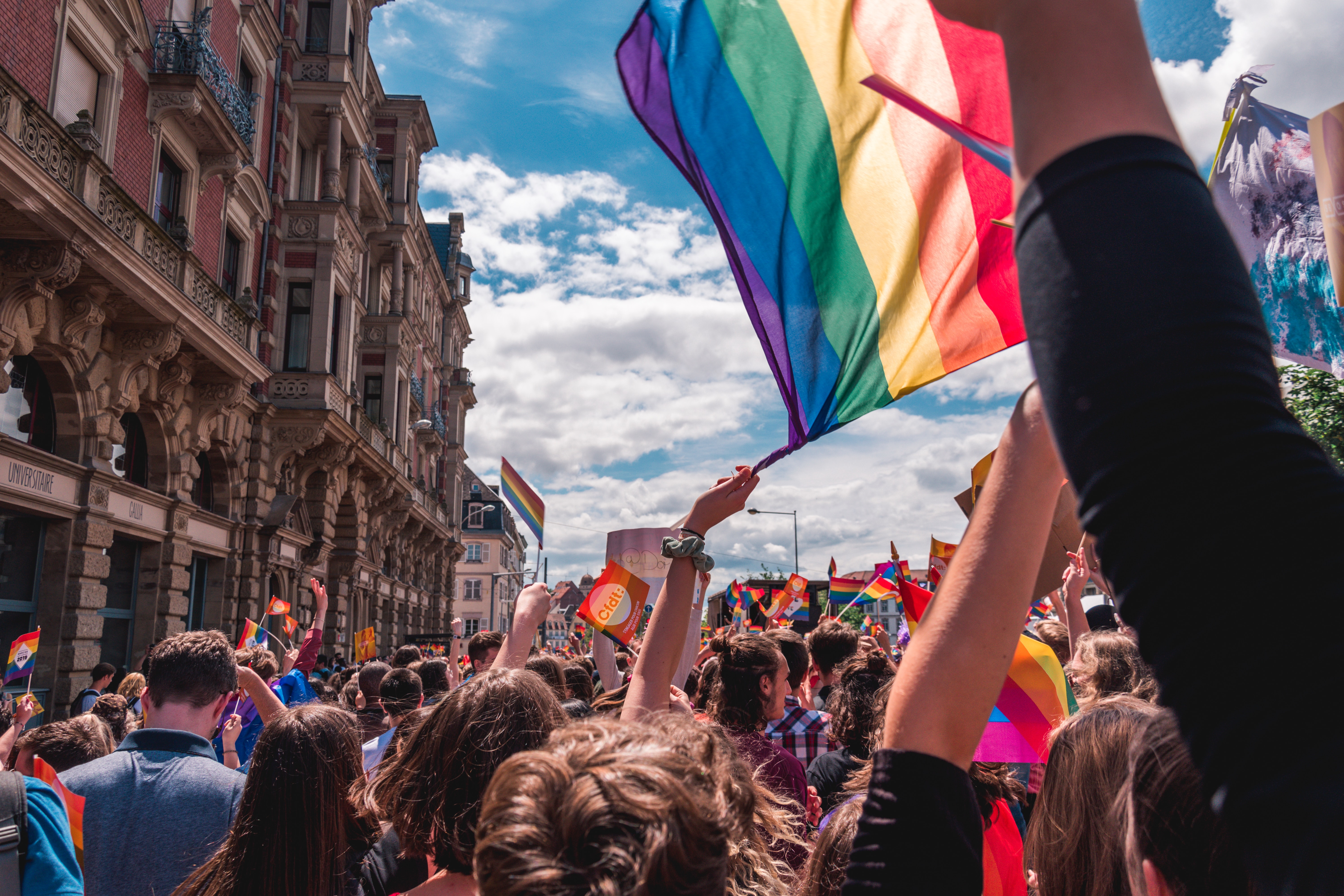 A crown of people at a Pride celebration, waving flags and looking joyful. Photo by Margaux Bellott.
