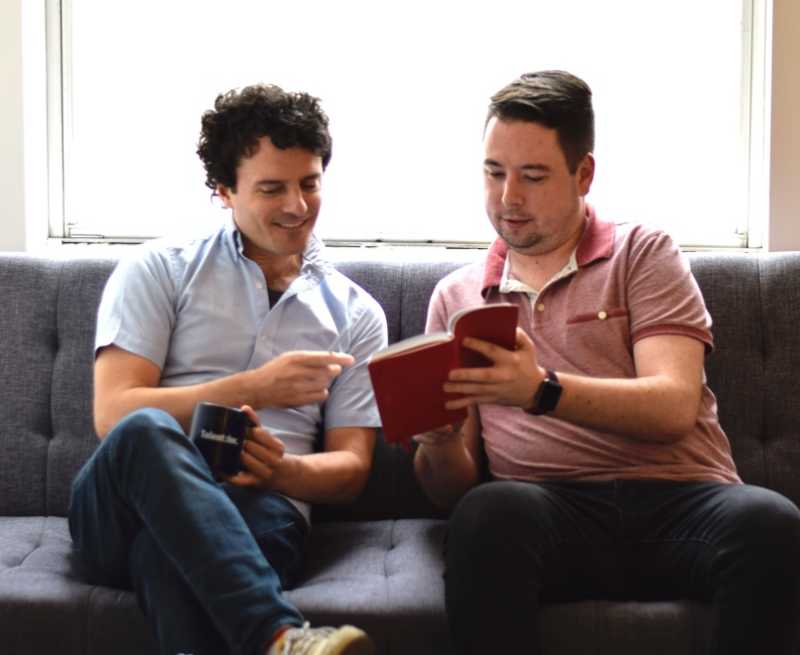 2 people looking at a book on a couch