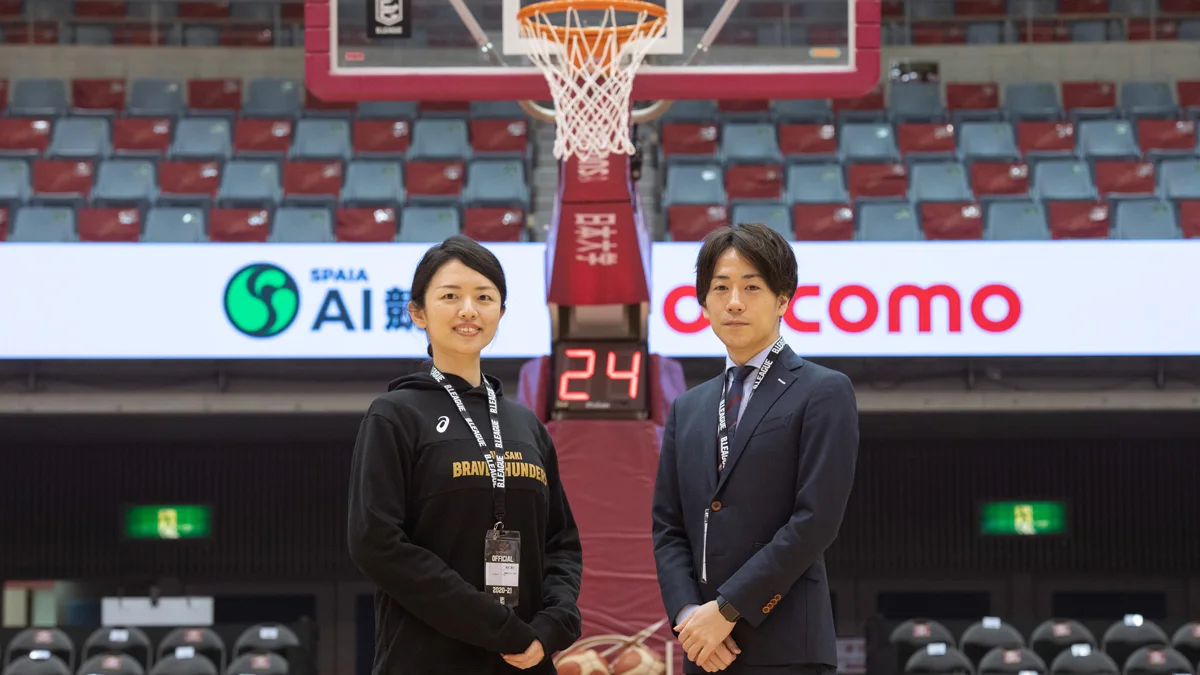 川崎ブレイブサンダースのホームアリーナのコート上に立つ取材対象者2名。背後にゴールとショットクロックが見える