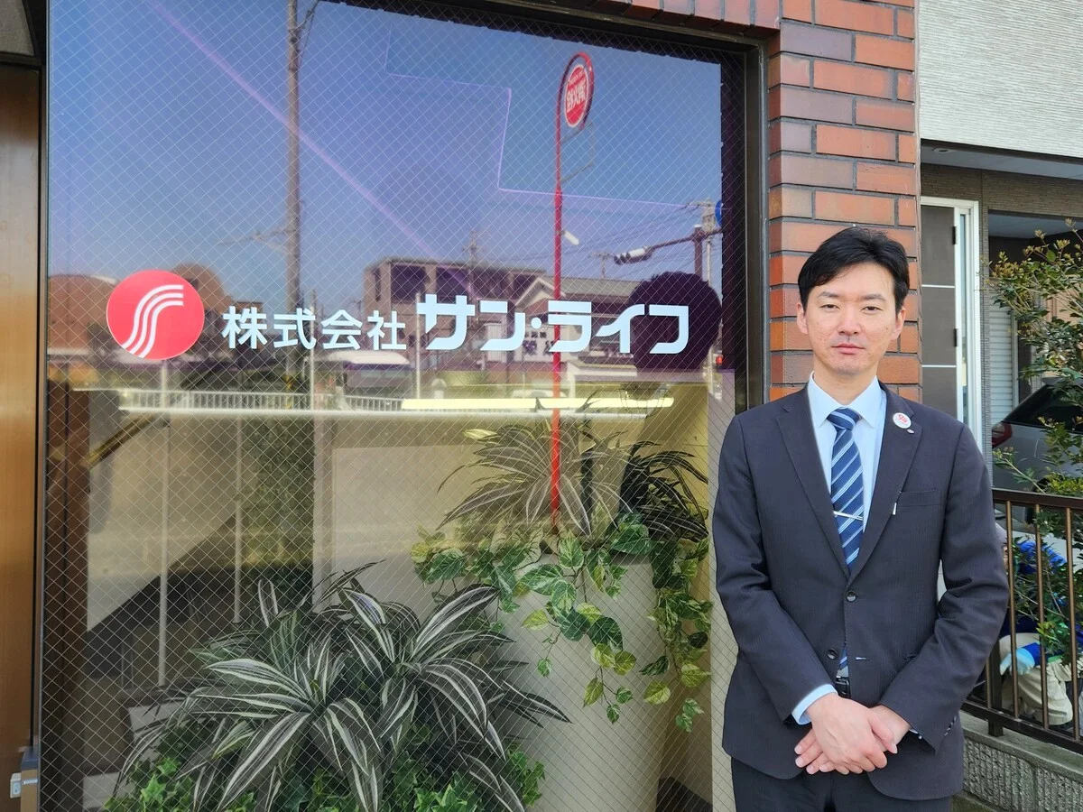 株式会社サン・ライフの社屋前に立つ取材対象者