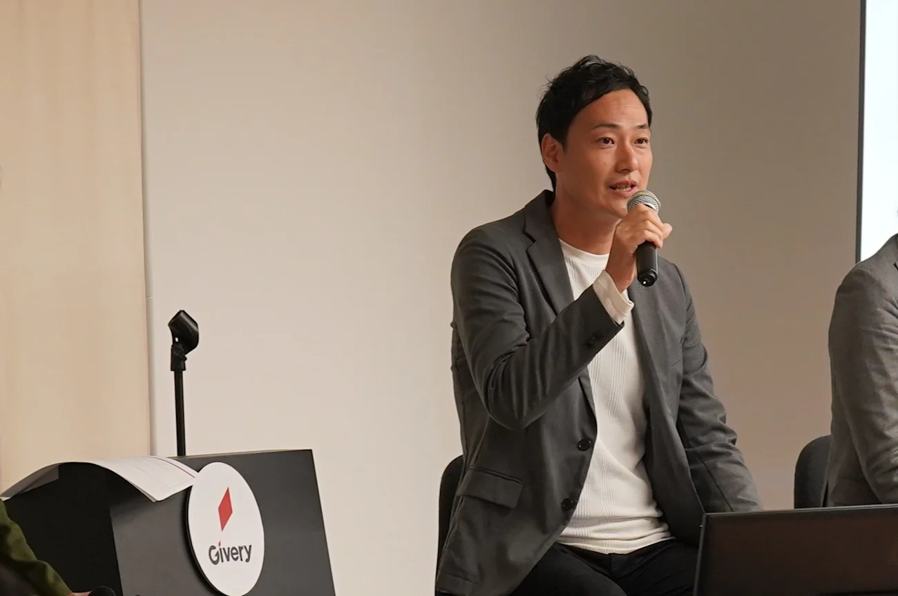 イベント登壇中の株式会社イリアルの登壇者。壇上でマイクを持って話している