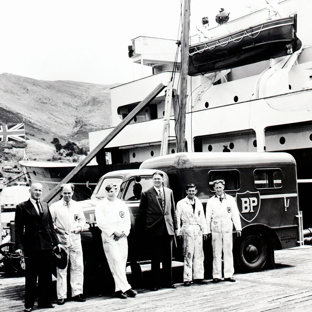 bp staff pose for a picture by the Royal Yacht Britannia in New Zealand, 1963