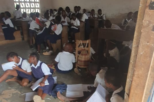 Niños estudiando en el suelo de un aula