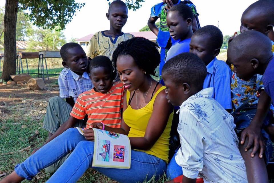 Woman reading a book to children surrounding her