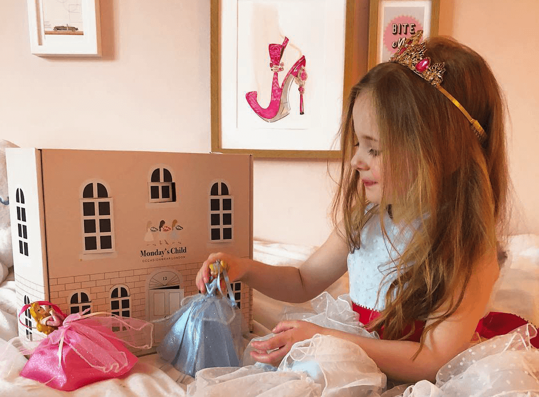 A photo showing a child playing with a dollhouse fashioned from packaging by Monday's Child