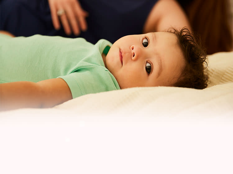 The child lies on the bed next to the mother