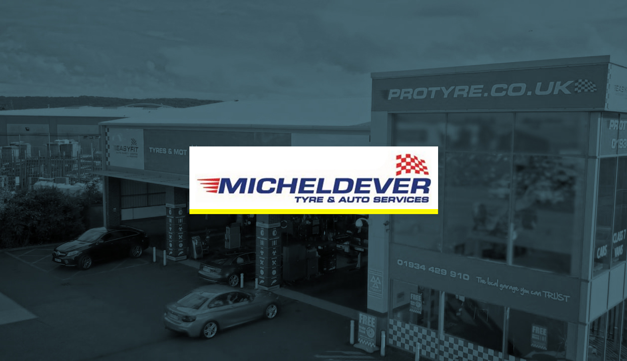 MichelDelver logo in front of an image of a car garage. The image has a blue overlay on it.