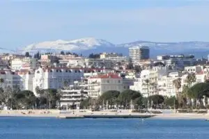 A view of Cannes showing the beaches along Croisette, the heart of the city, and a mountain backdrop.