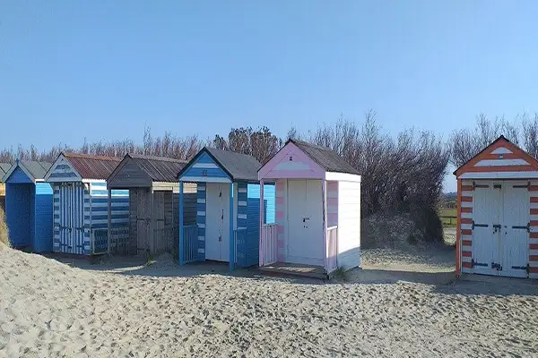 Colorful beach huts against the dunes with an enviable beachside setting.