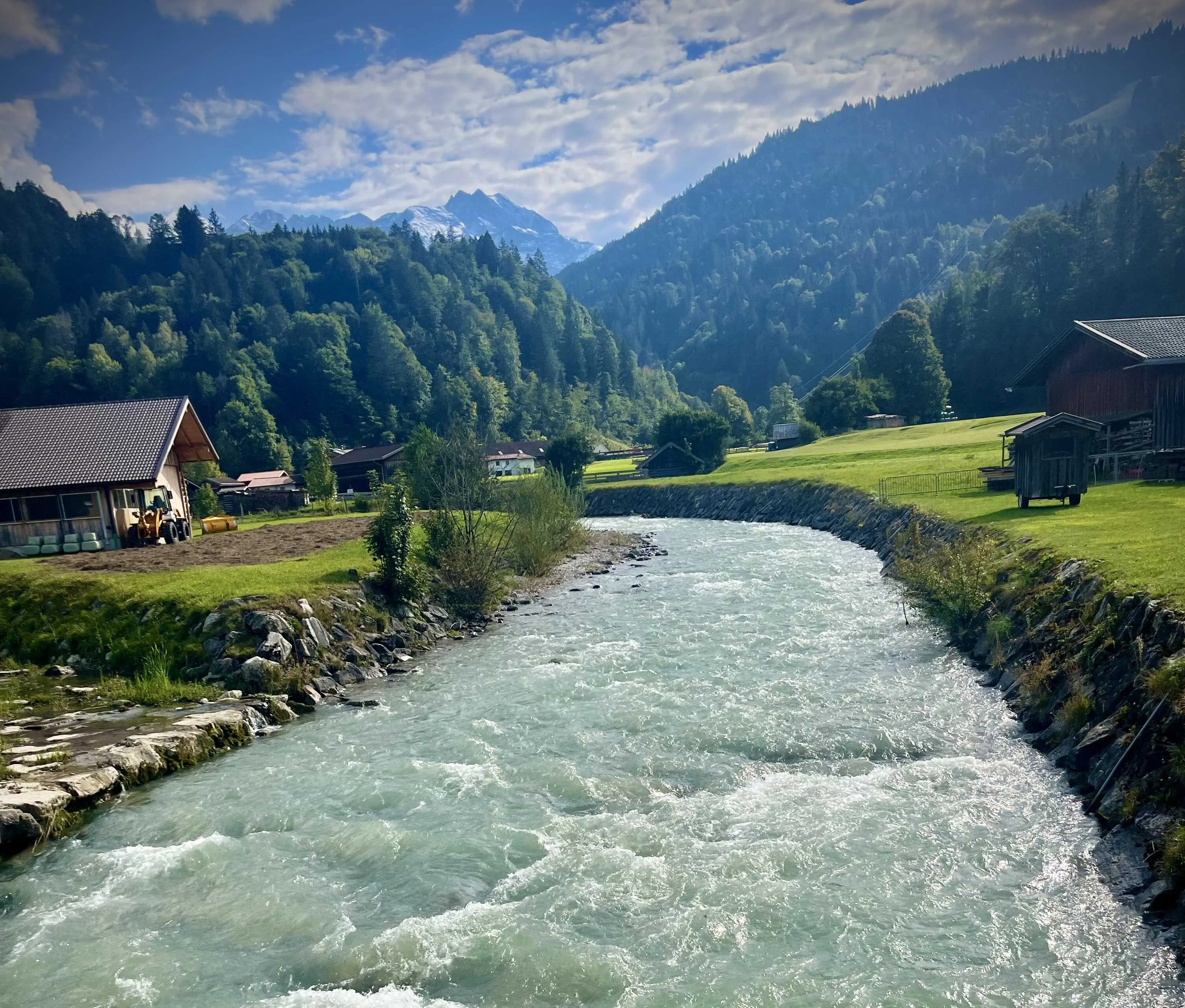 Alpine waters wind through Garmisch’s lush valley framed by traditional homes.