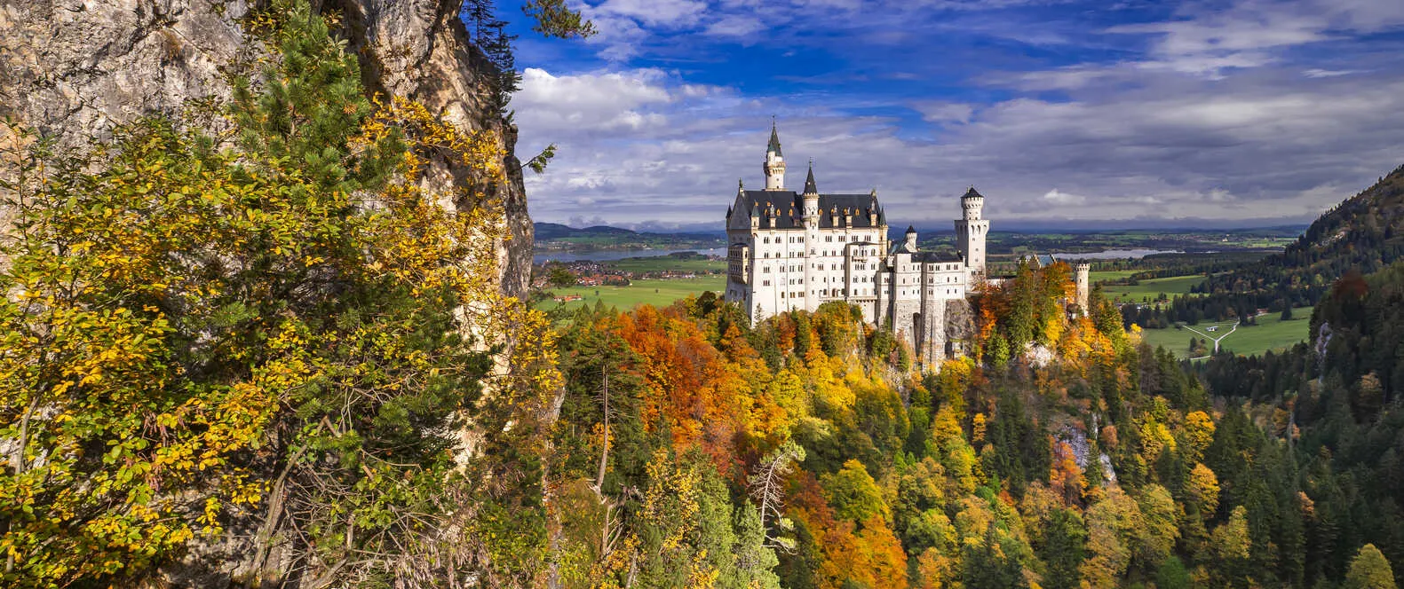 Neuschwanstein Castle stuns in autumn, Germany’s real-life fairytale above the forest.