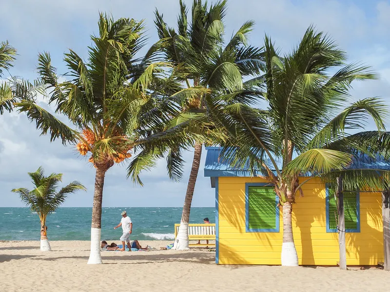 Colorful beach huts and swaying palm trees in Placencia, Belize.