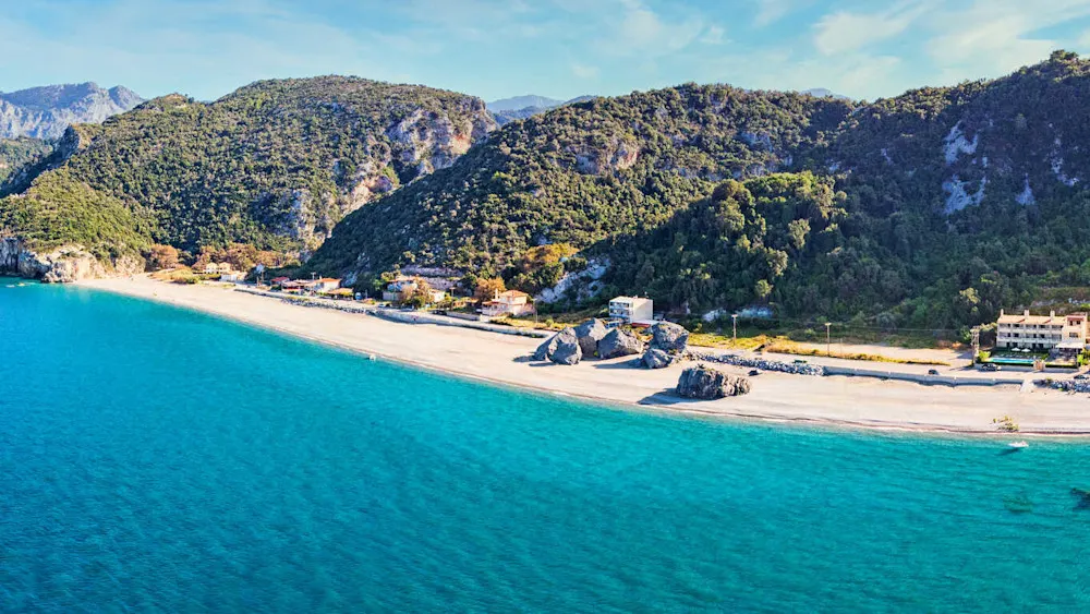Chiliadou Beach—crystal-clear waters framed by steep cliffs and pines.