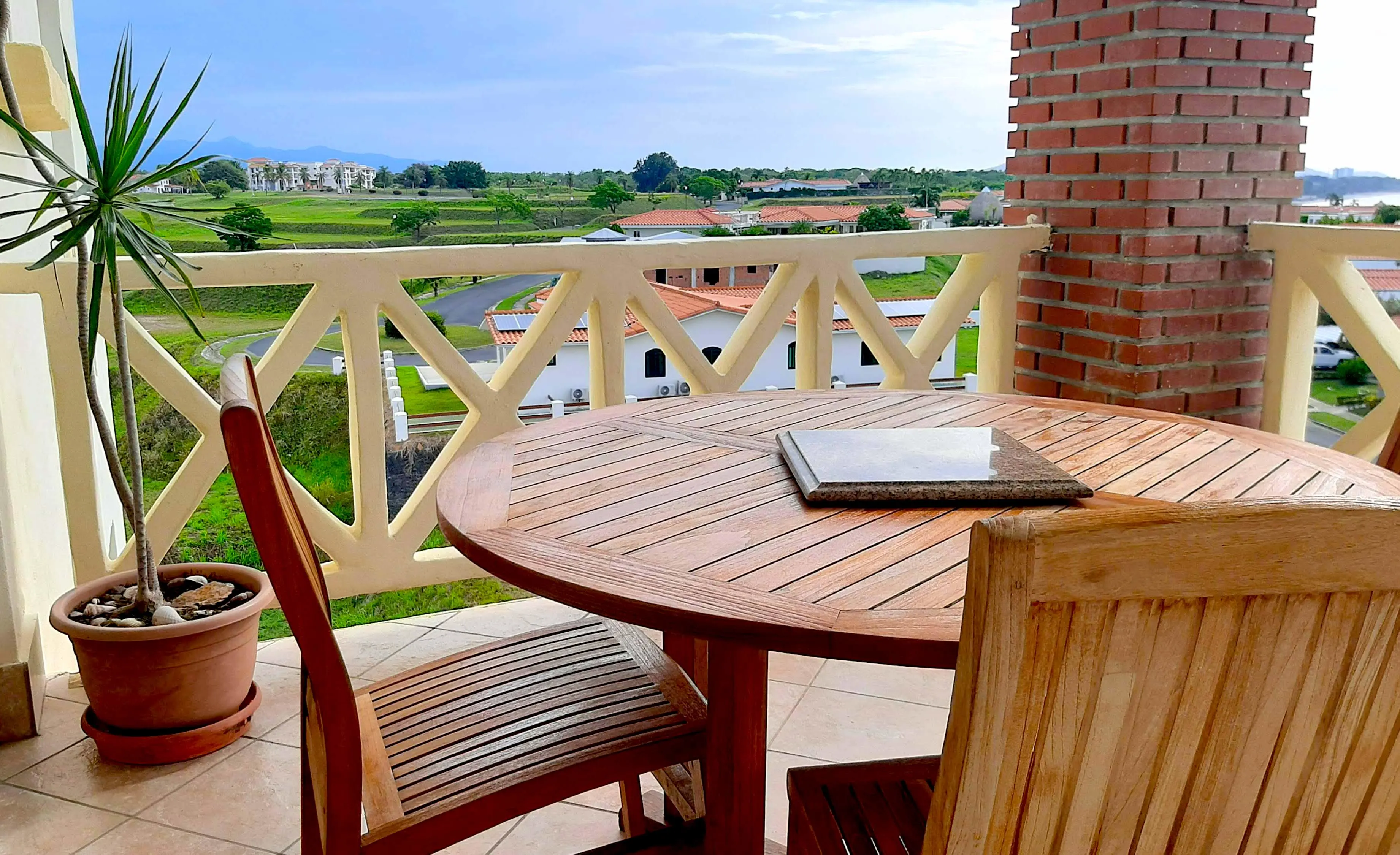 Jess’ $155K apartment offers stunning views of a golf course, beach, and tropical Pacific, with mountains in the background.