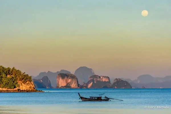 View from Ko Yao Noi of a longtail boat, the full moon, and limestone karsts at sunset, Phang Nga Bay.