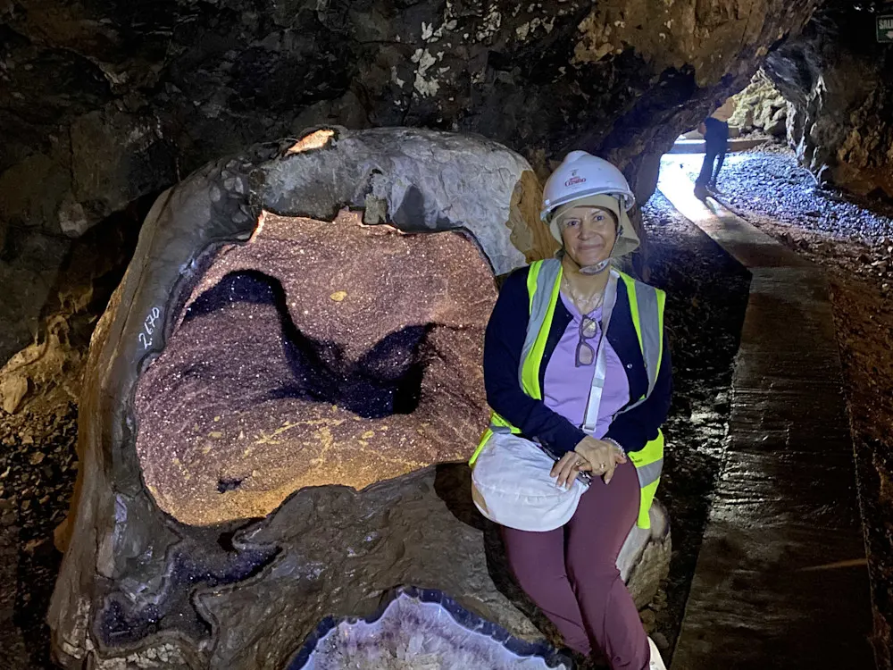 A color-coordinated “miner” poses with a giant amethyst geode.
