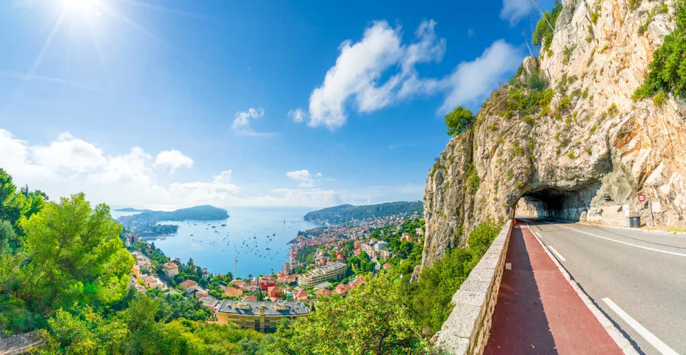The scenic corniche road winds through cliffs and palms along the Côte d’Azur.