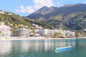 A more modern side of Menton: Condo buildings close to the beach and boardwalk with mountain peaks as a backdrop.