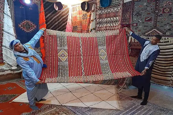 Aziz (left) and his assistant, Abdo, display some of their beautiful, hand-crafted tapestries at Aziz Maison de Treasol, in the ancient caravan trading town of Rissani. ©David Gibb