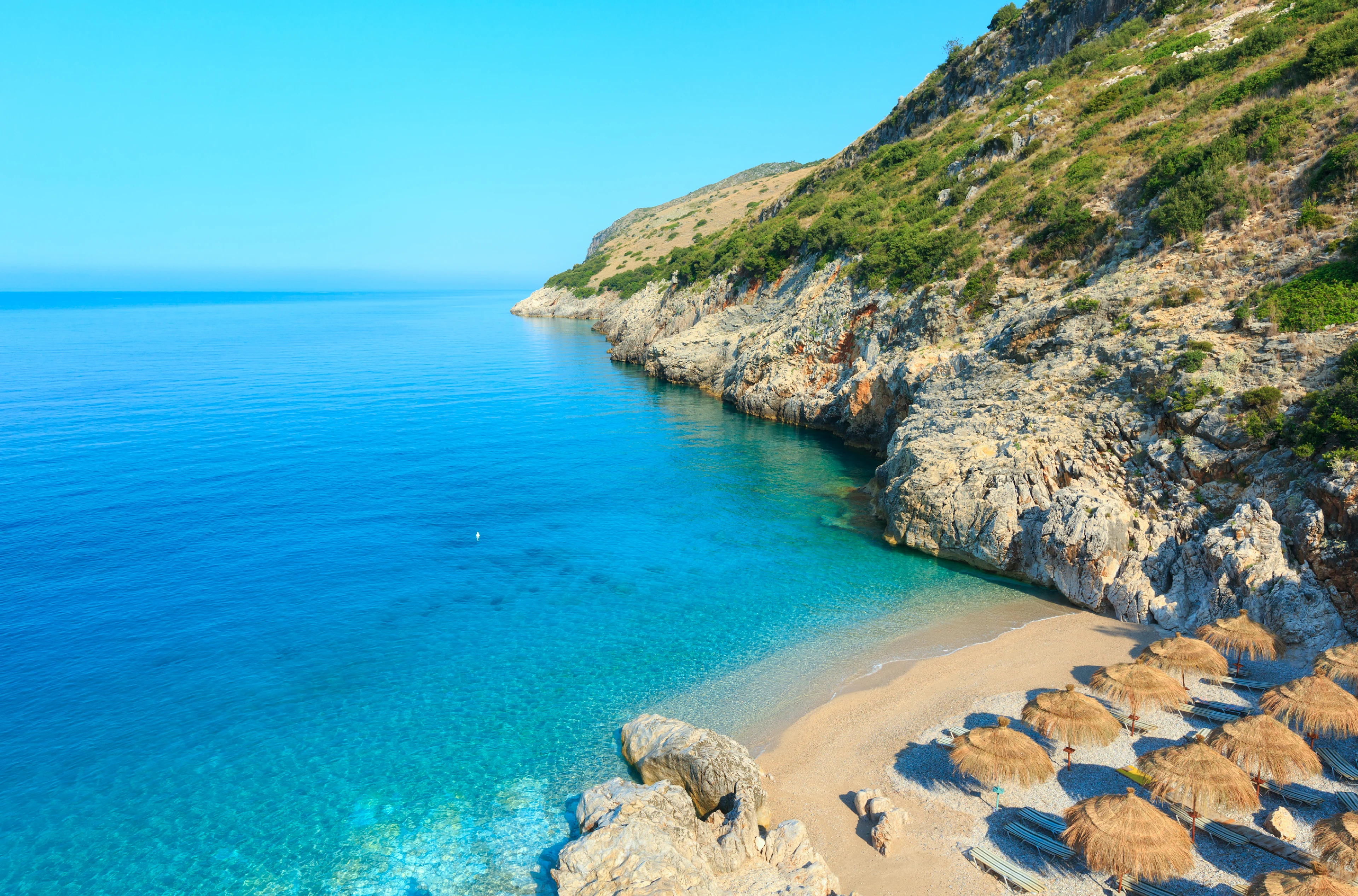 liten strand i Albania med parasoll og omgitt av fjell