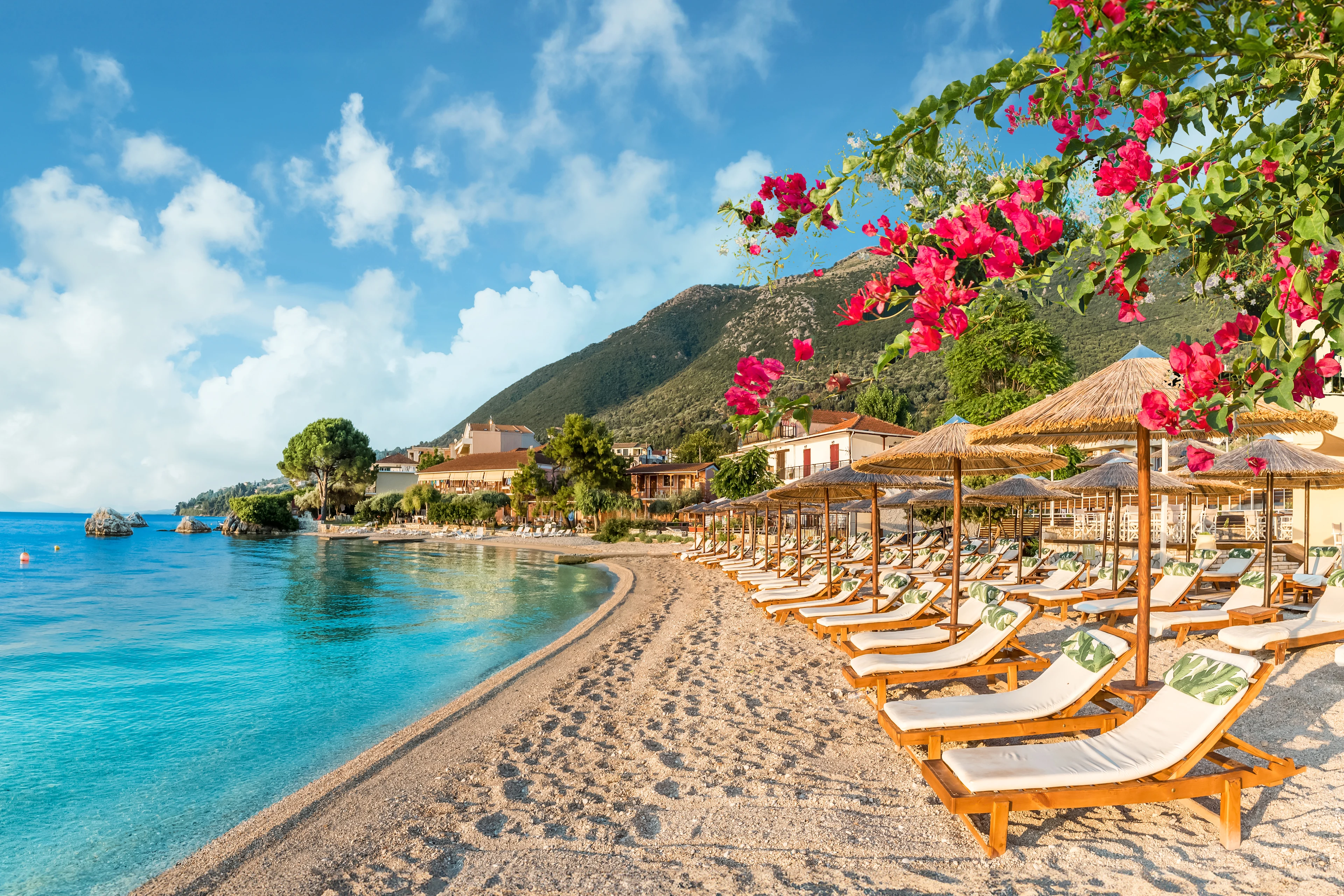 Solstole på en smuk strand med grønklædte bjerge i baggrunden på Lefkas