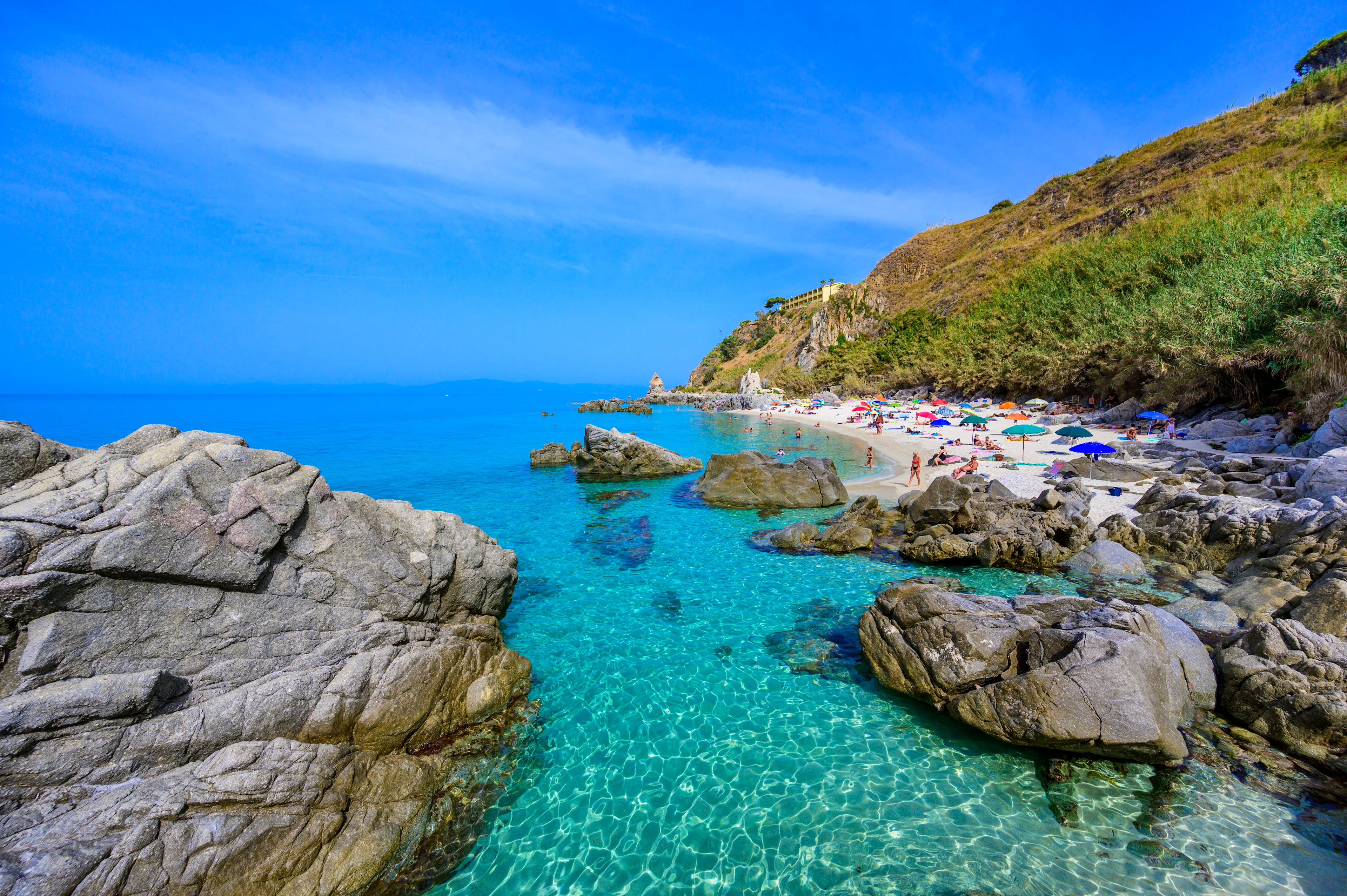Vy över en vacker strand med klippor och kristallklart vatten i Kalabrien