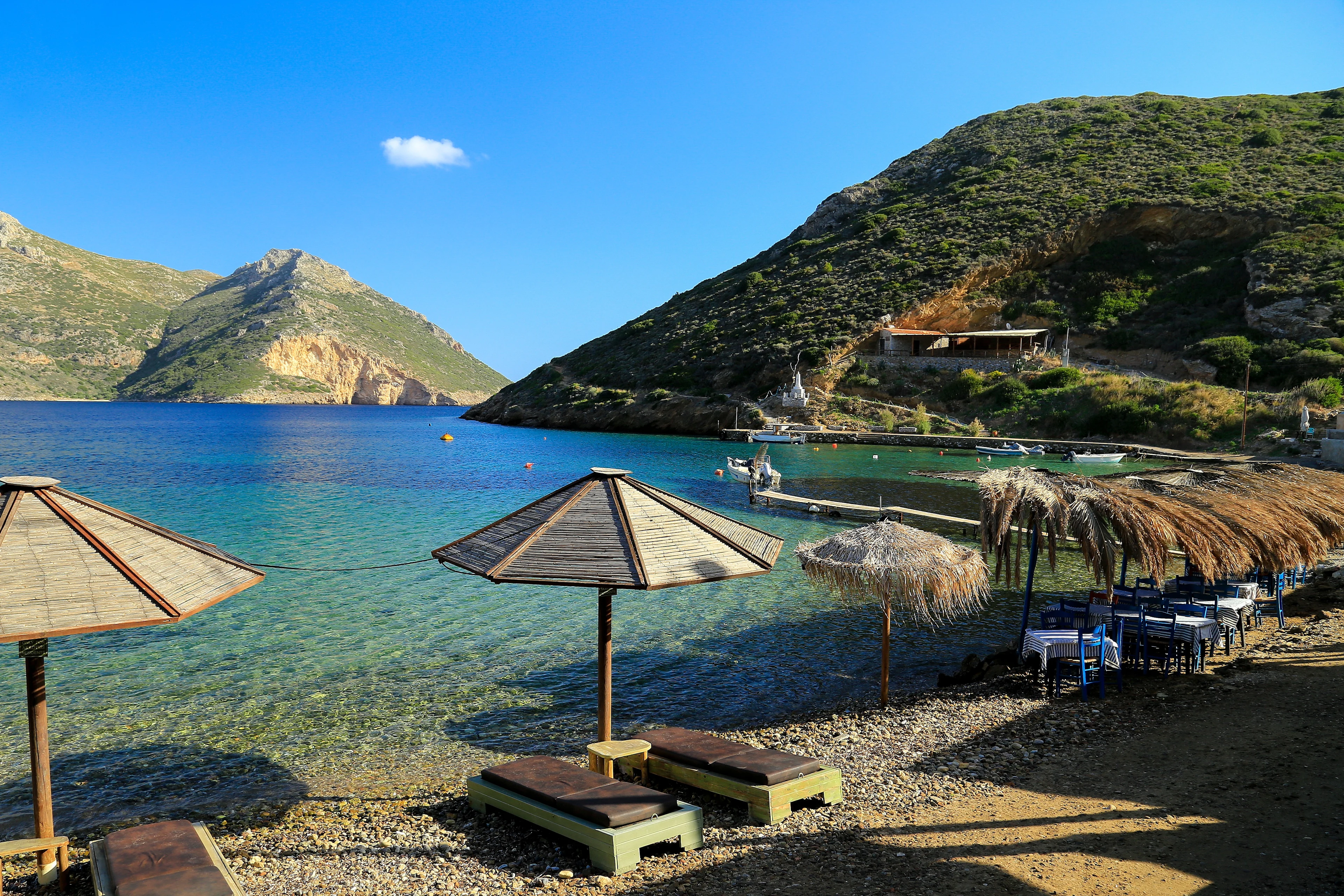 Solsenger og parasoller av strå på stranden Karathona