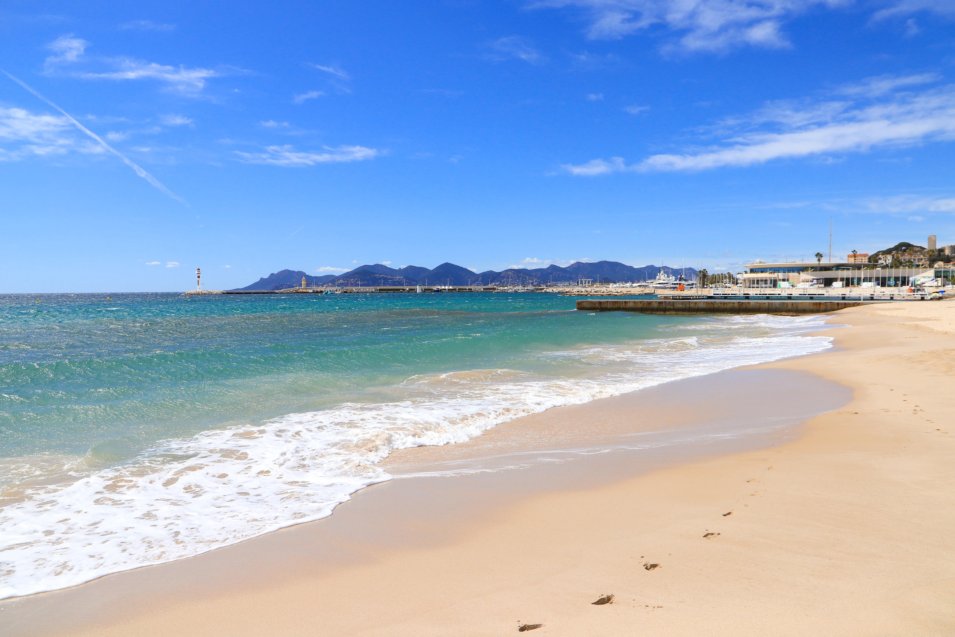 Plage du Midi i Cannes på Franska rivieran med ljus sandstrand, turkost Medelhavsvatten och utsikt över stadens kustlinje.
