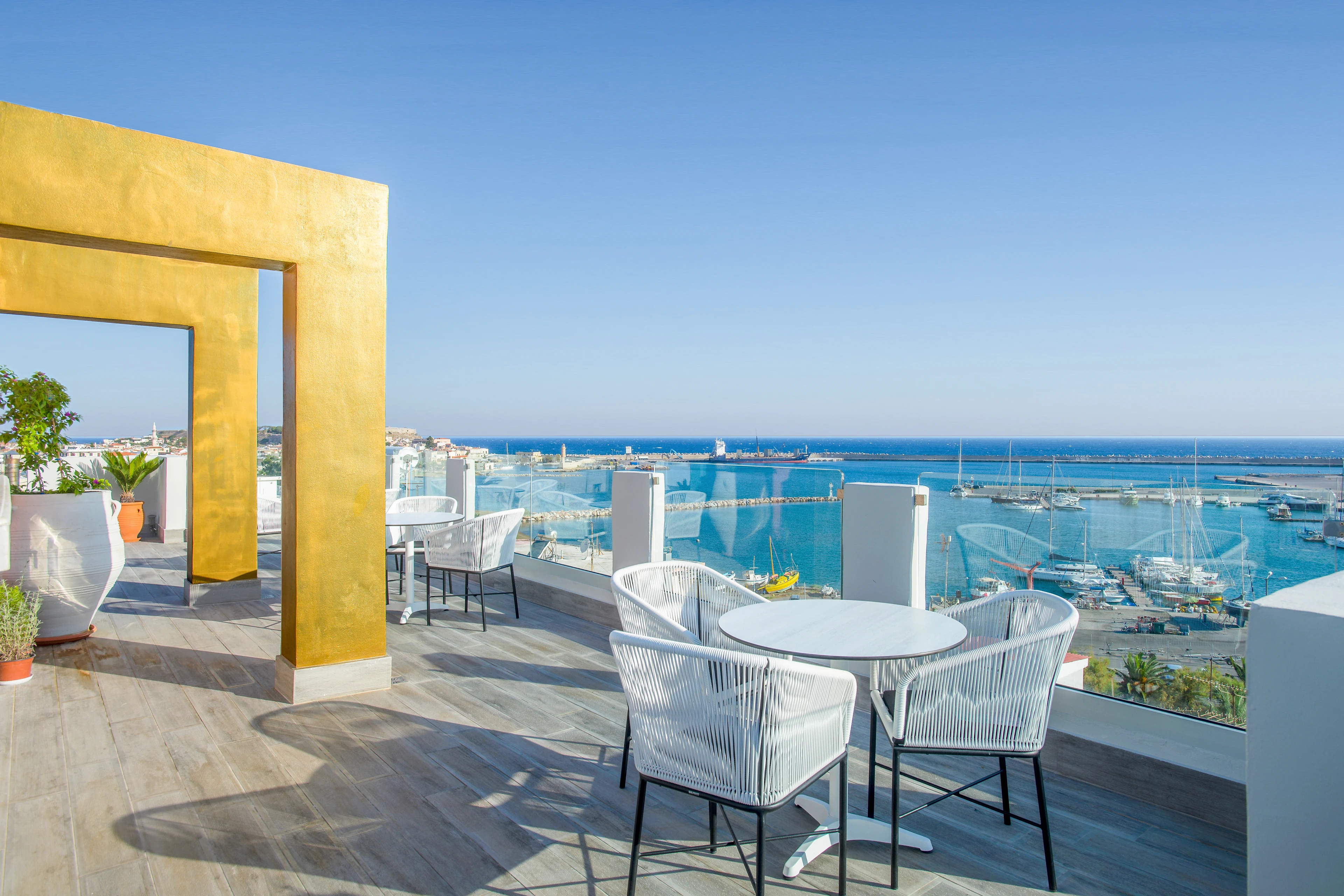 Terrass med sittgrupp och utsikt över havet och hamnen på Blue Sea Apartments.