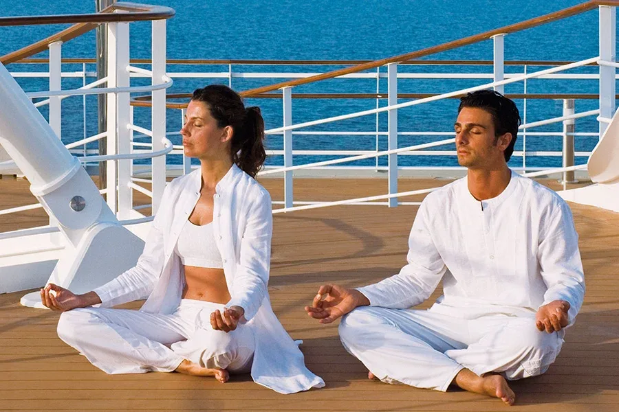 Par som utför yoga ute på däck